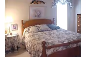 A floral-patterned bed with a wooden headboard in a softly lit bedroom.