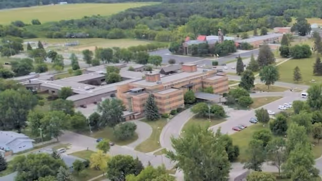Aerial view of a Benedictine Living Community-Crookston campus with brick buildings and green surroundings.