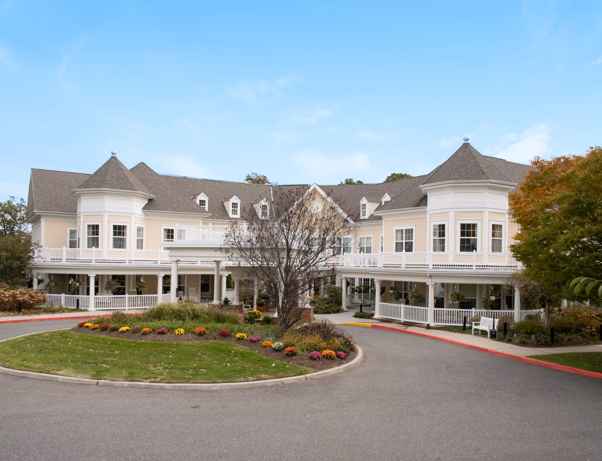 Sunrise of East Setauket exterior shows a large, cream-colored residential building with a circular driveway.