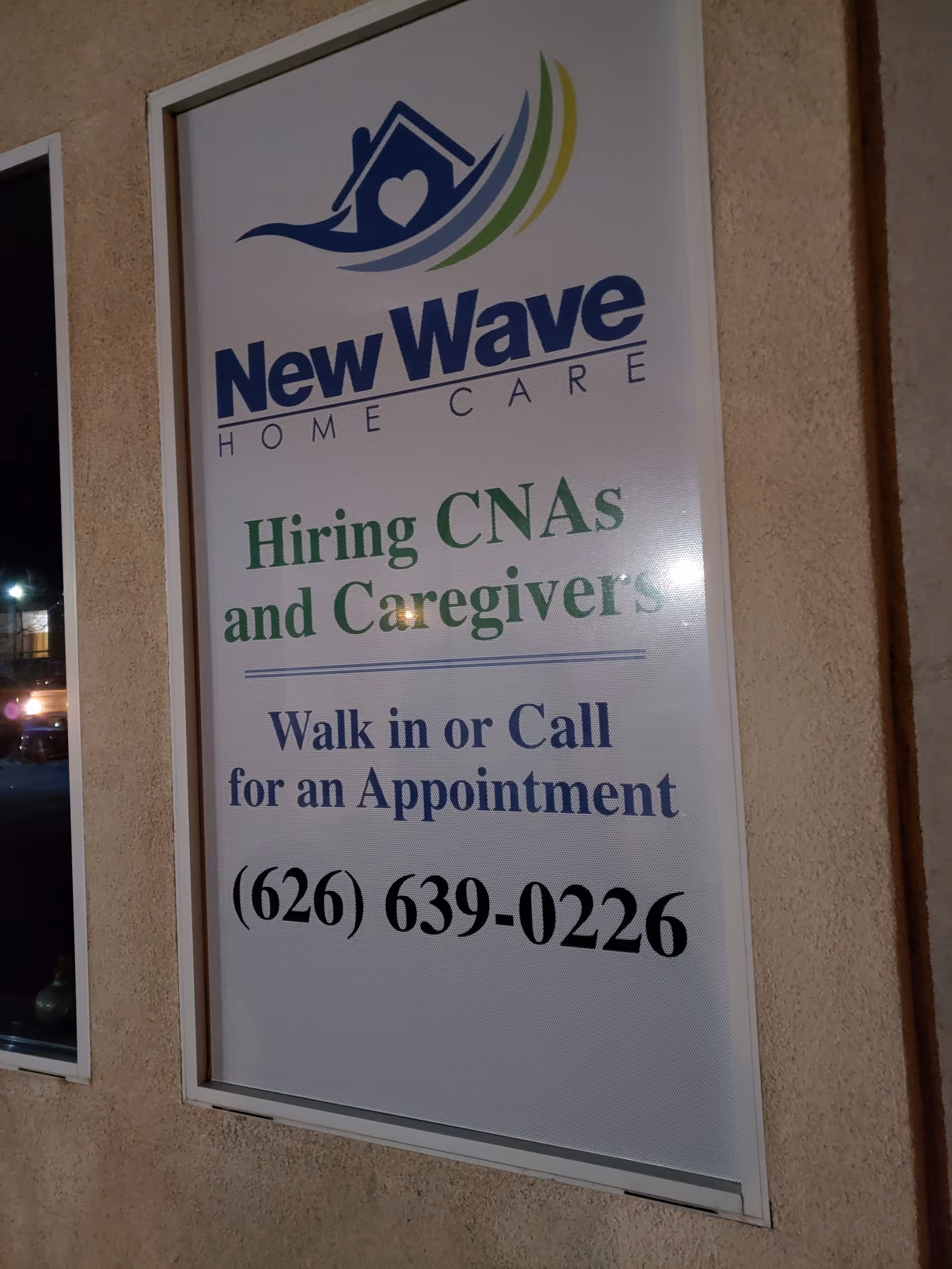 Exterior sign advertising New Wave Home Care, hiring CNAs and caregivers, with appointment phone number