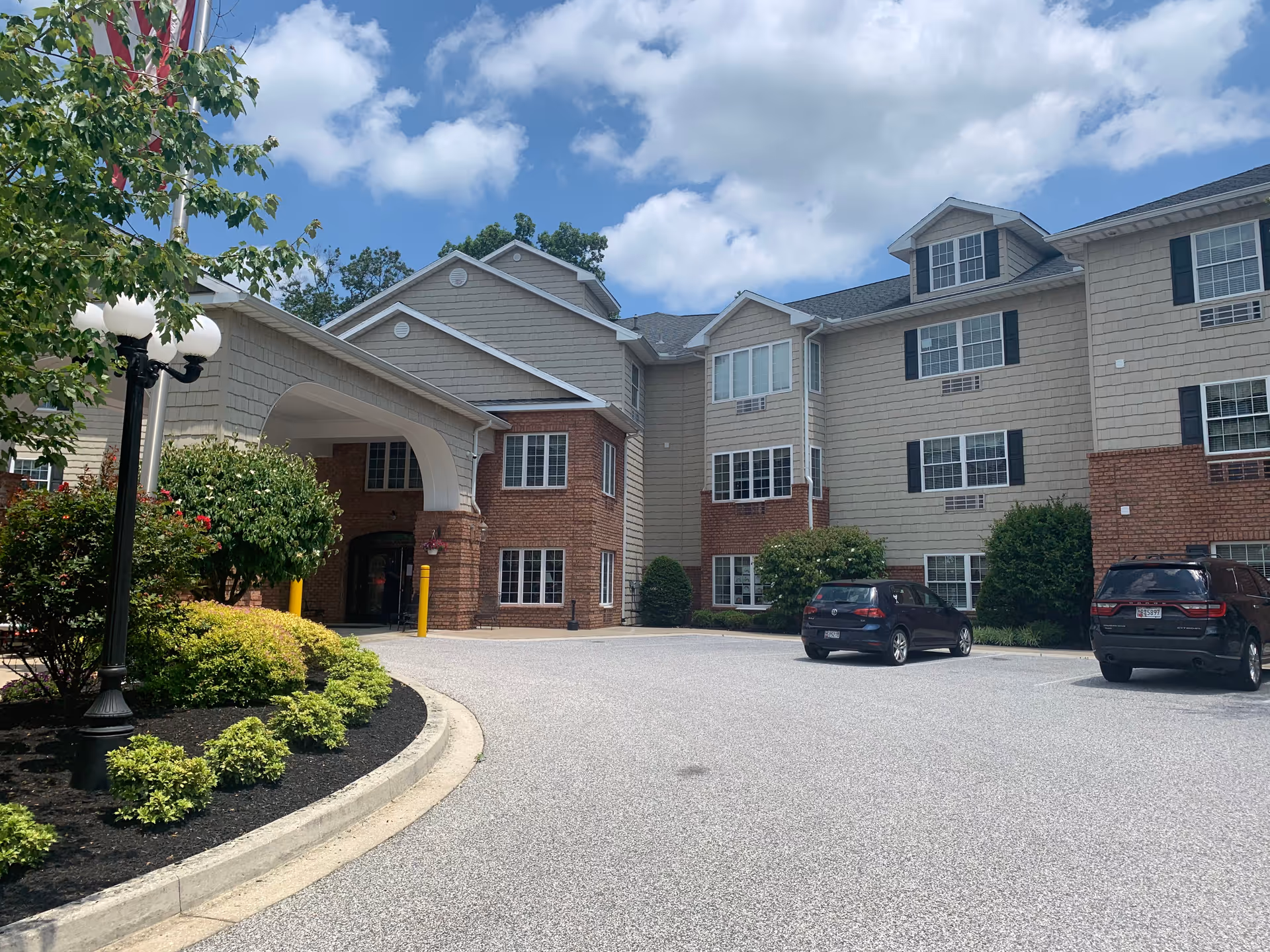 Exterior view of a Hart Heritage Estates senior living building with a curved entrance and cars.