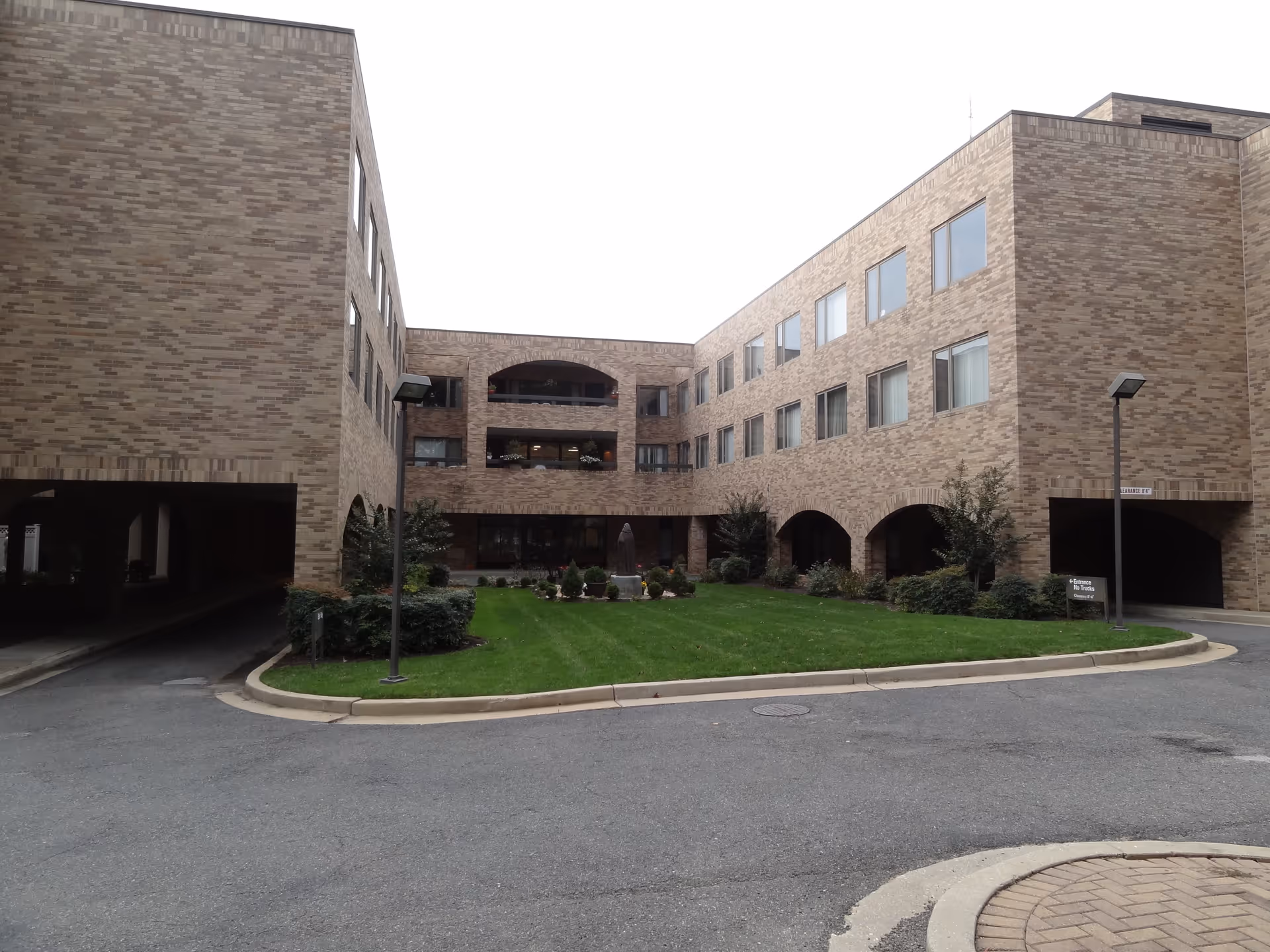 U-shaped brick senior living building surrounding a manicured green courtyard.