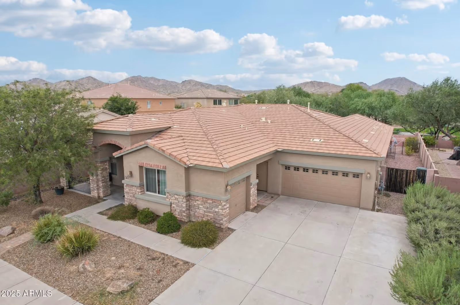 Aerial view of a tan stucco senior living facility with red-tiled roof and driveway.