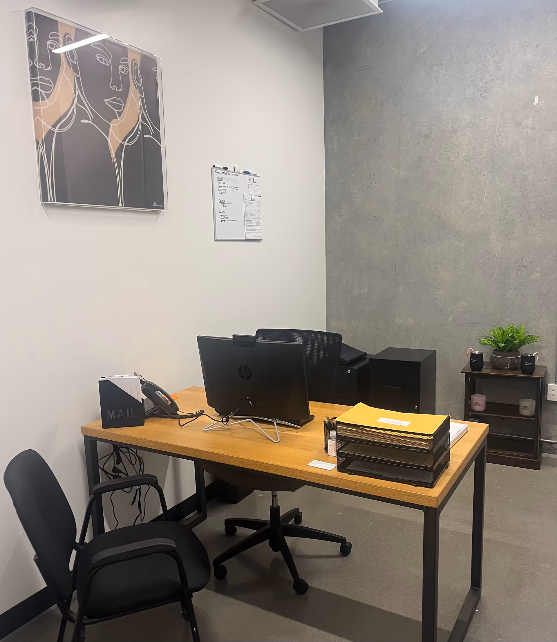 A wooden desk with computer, chair, and office supplies in a small, modern office.