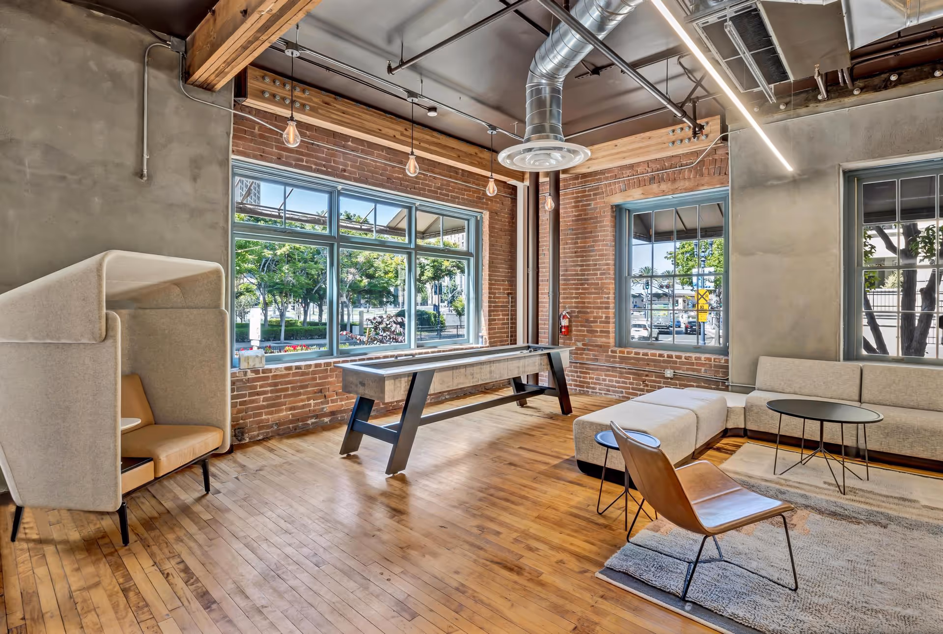 Industrial-style lounge with brick walls, large windows, hardwood floor, and contemporary seating.