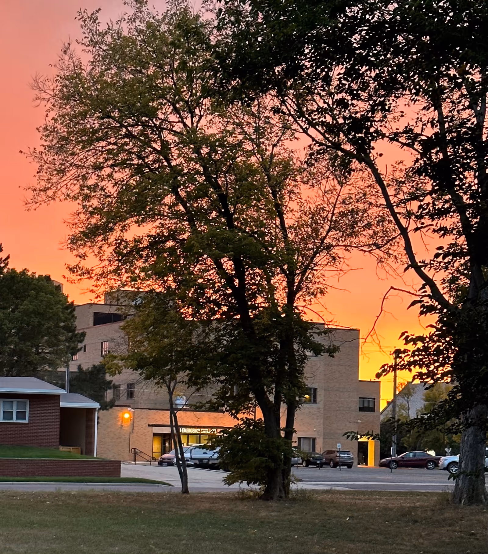 Sunset behind the brick Huron Regional Medical Center exterior with trees.