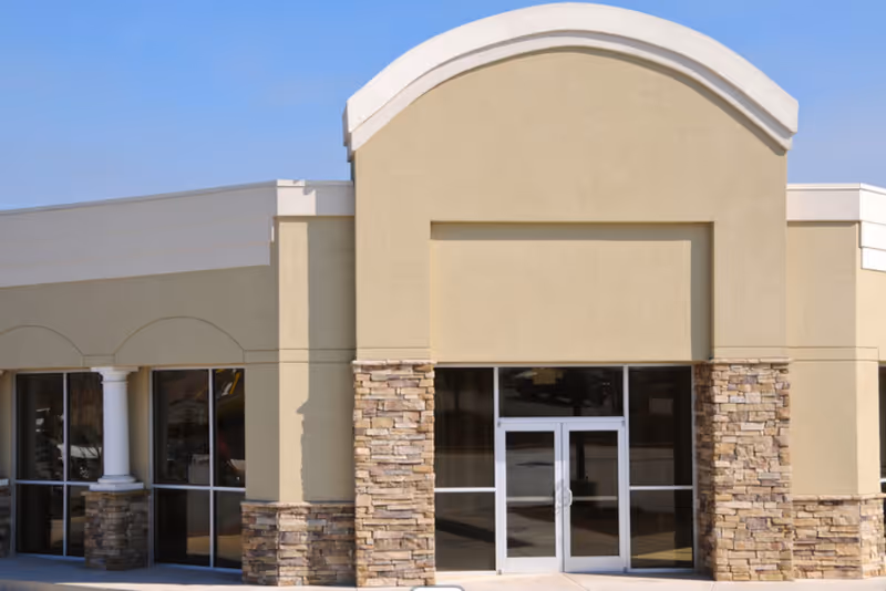 Front view of a beige senior living facility with glass doors and stone columns.