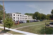 Exterior view of Woodbine Rehabilitation & Healthcare Center, a white multi-story building with a parking lot.