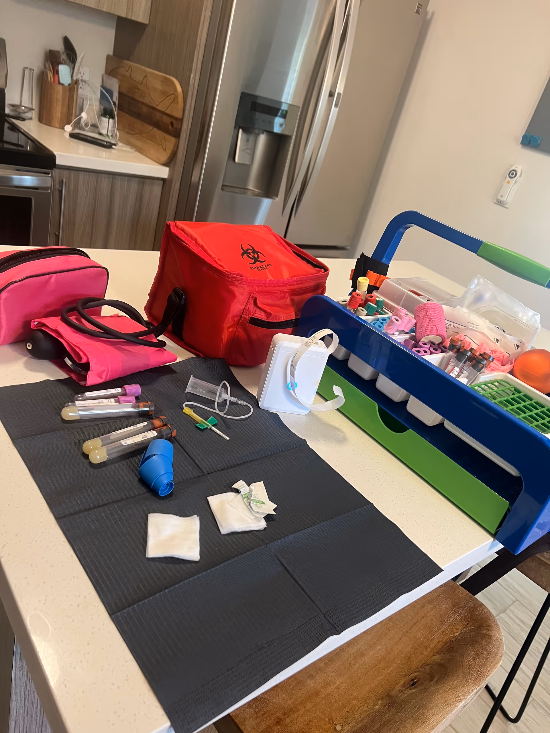 Phlebotomy supplies arranged on a kitchen island with a red biohazard bag and tools.