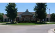 Front view of Villa Maria senior living entrance with two tall trees and lawn.