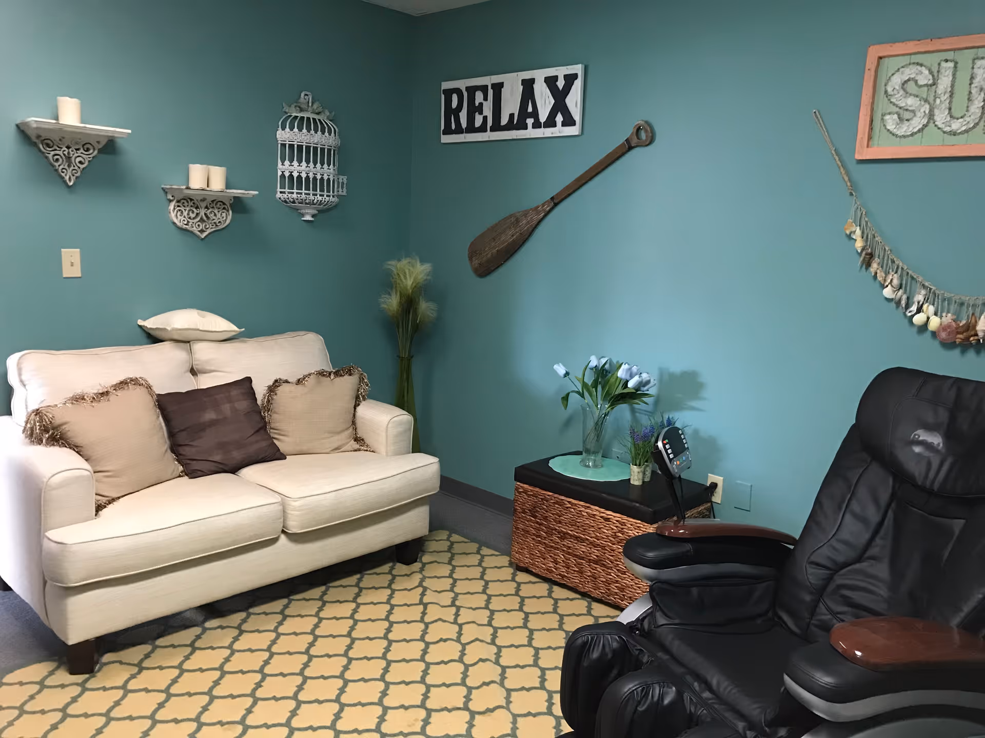Teal-walled living room with cream sofa, massage chair, and RELAX sign.