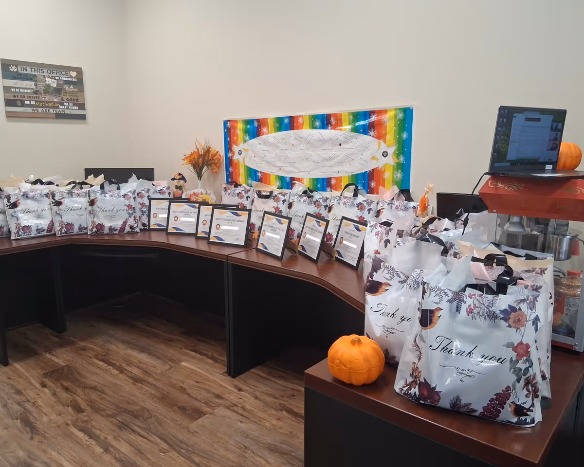 Curved reception desk lined with gift bags, certificates, pumpkins, and a colorful backdrop.