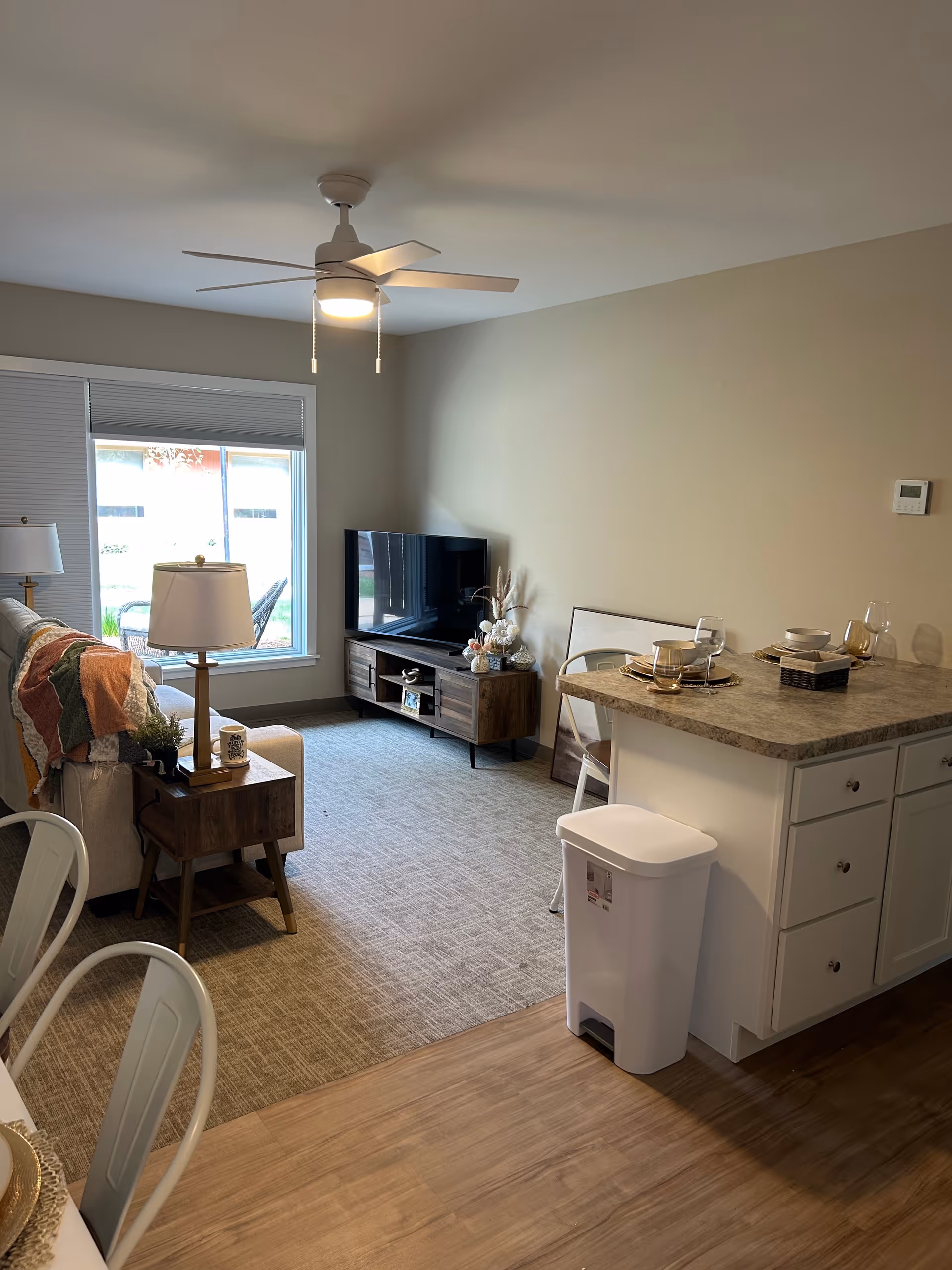Open-concept living area with sofa, TV, dining table, and kitchen island.