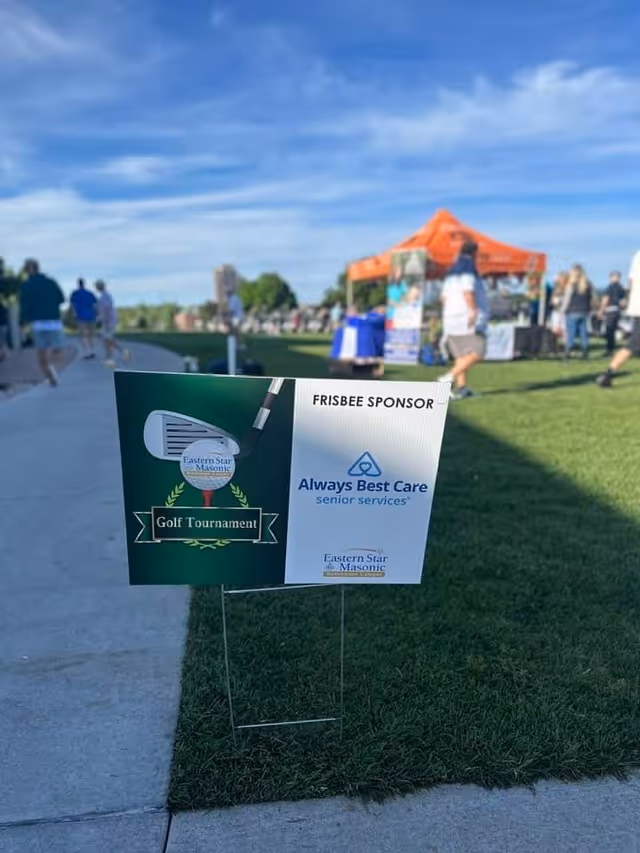 Outdoor event with sponsor signs for Always Best Care Senior Services at a golf tournament.