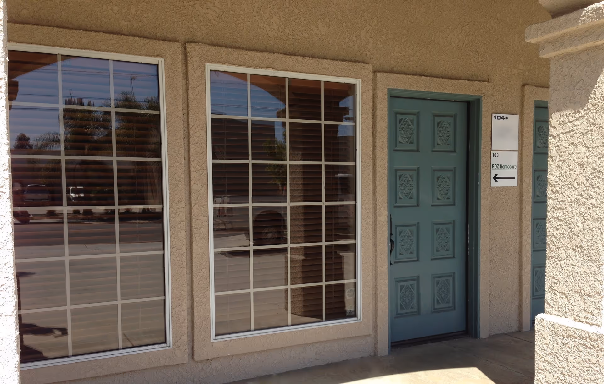 Exterior view of RozHomeCare entrance with blue door and large window panels.