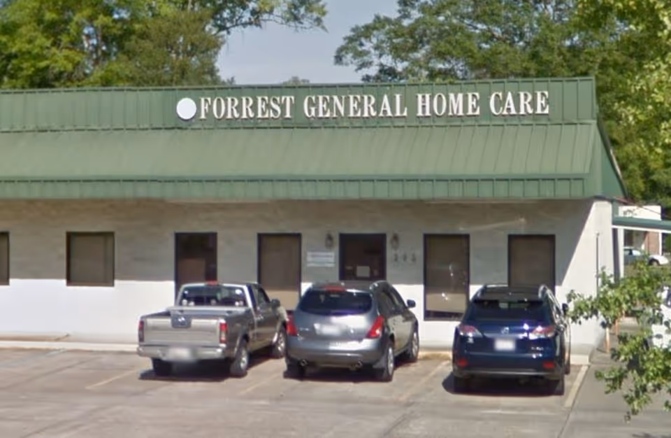 Green-roofed Forrest General Home Care building with a parking lot in front.