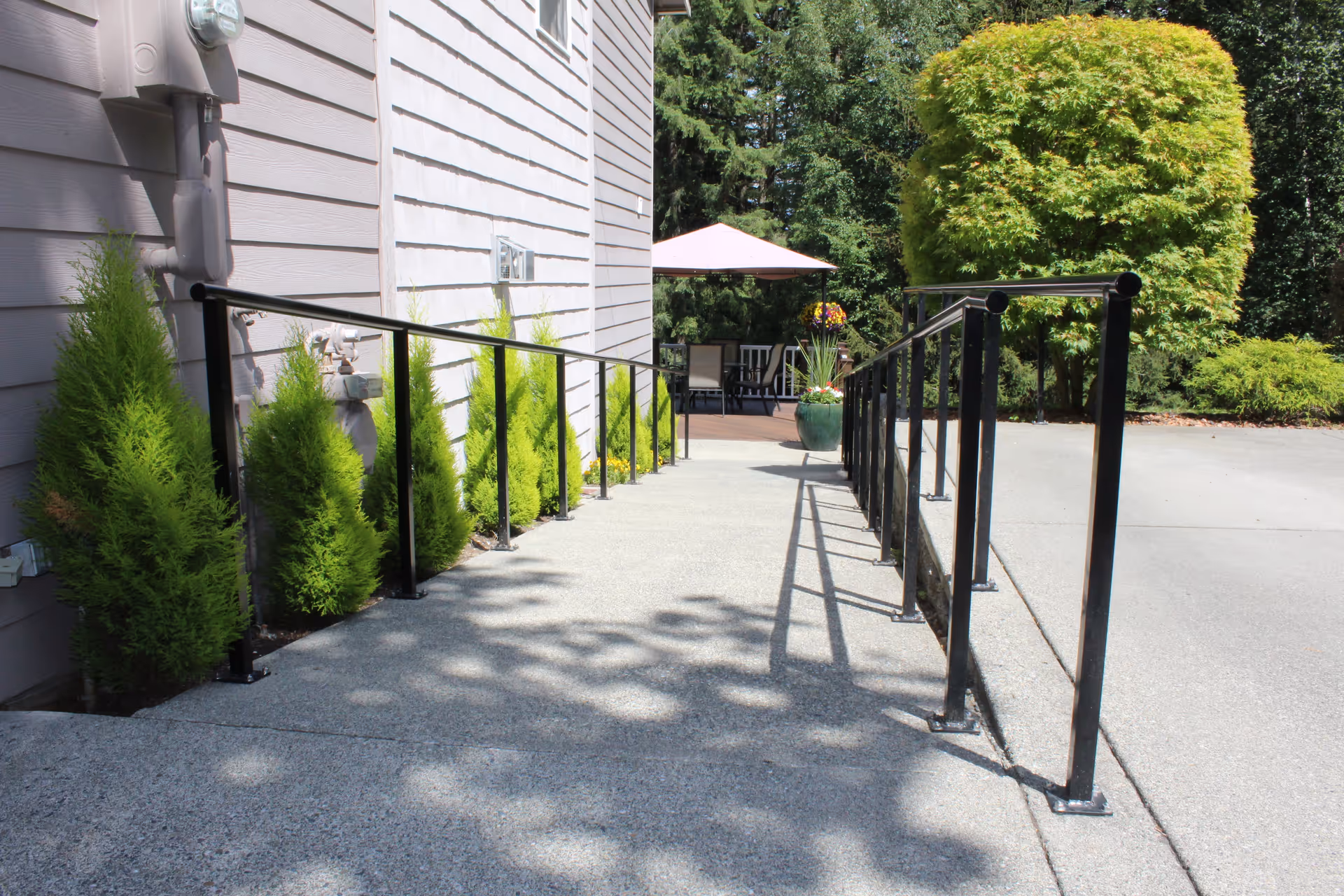 Outdoor ramp leading to a patio with table and umbrella beside a beige building.