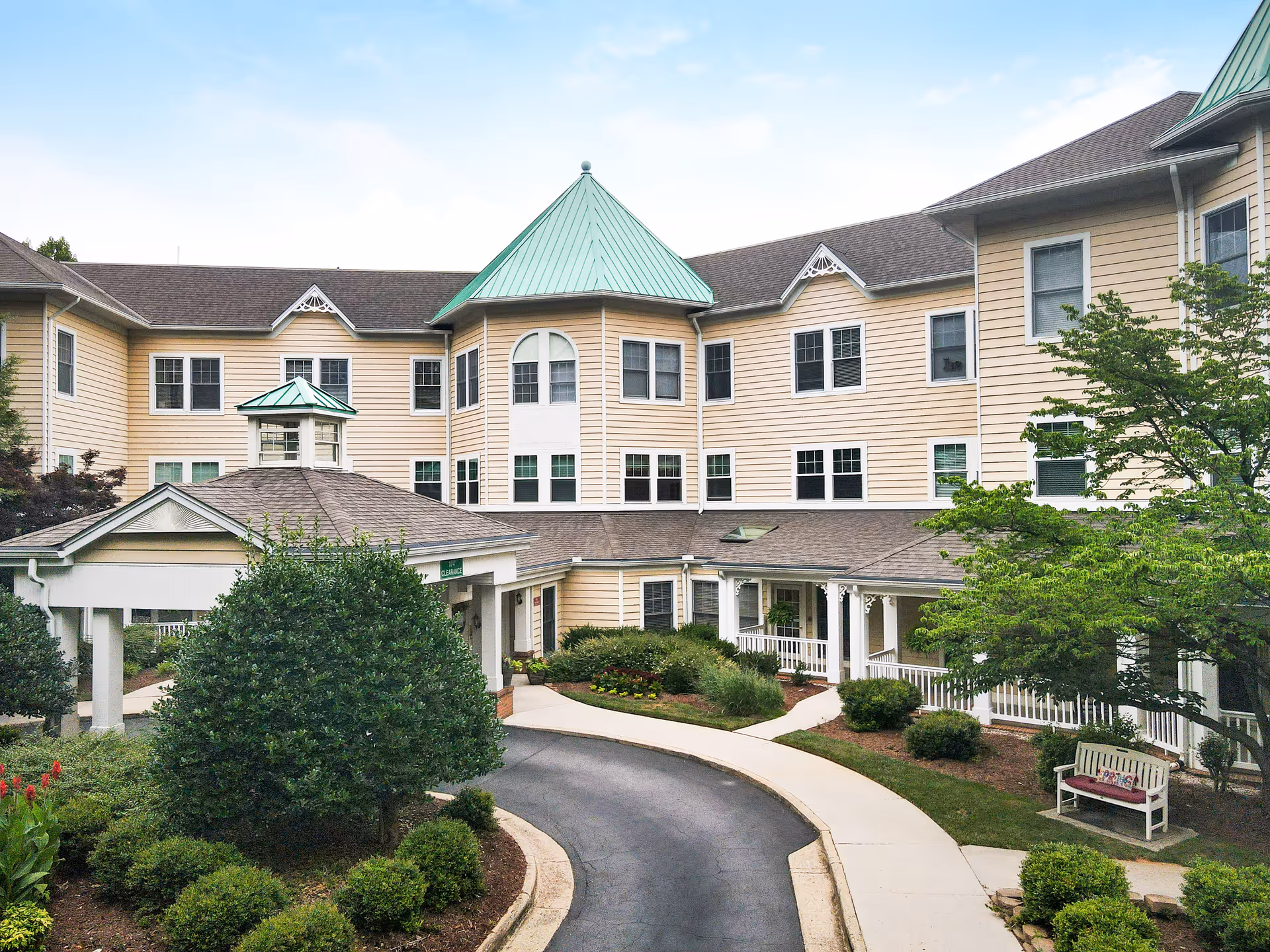Sunrise of Raleigh senior living facility exterior with beige siding, green roof, and landscaped entrance.