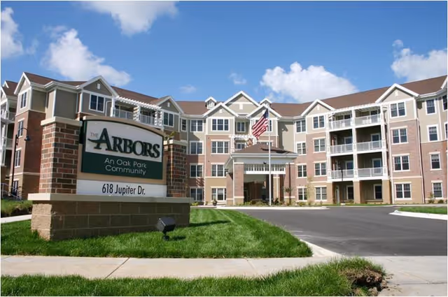 Exterior view of The Arbors senior living community with sign and entrance.