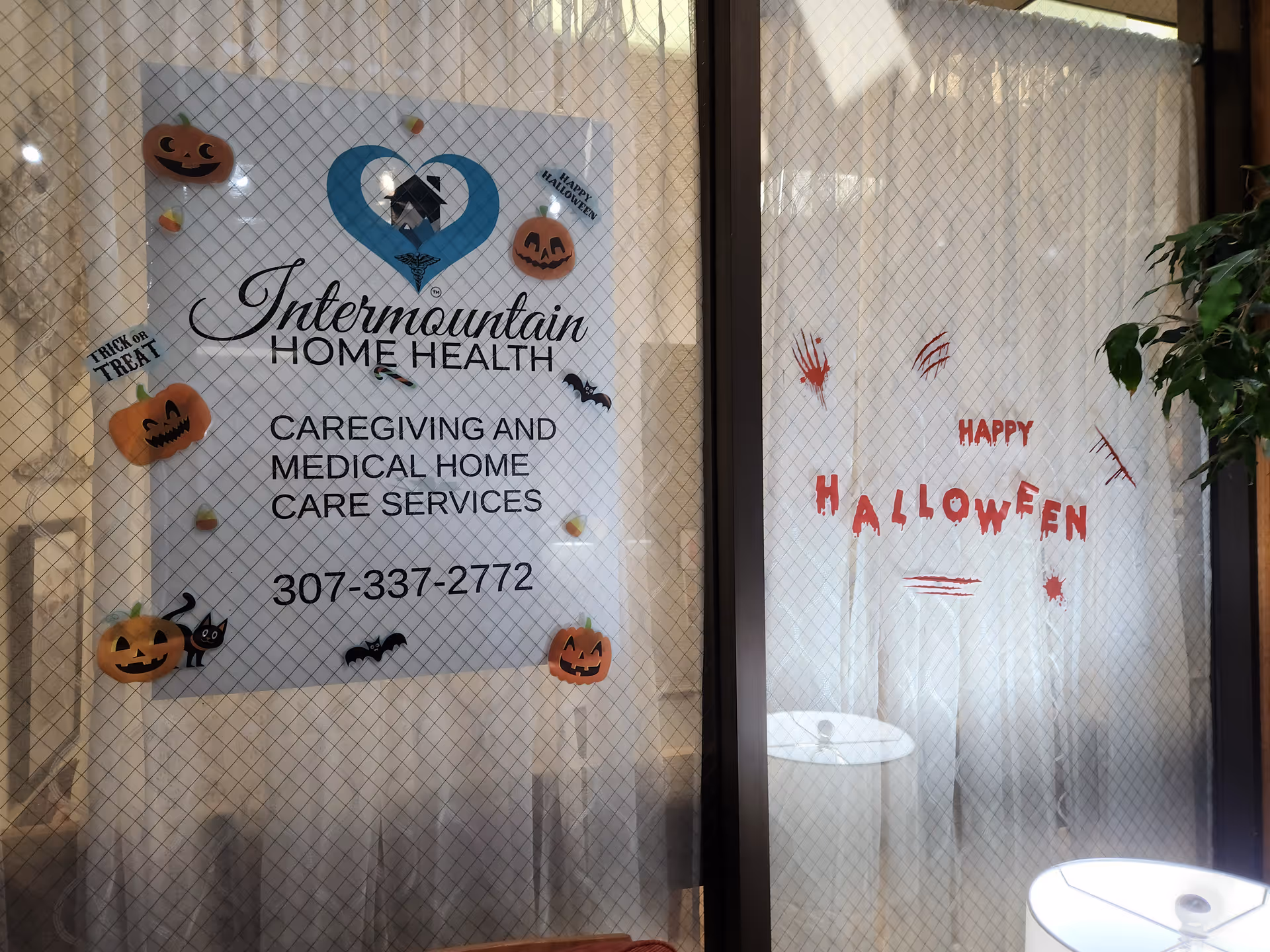 Glass storefront window displaying Intermountain Home Health sign with Halloween decorations.