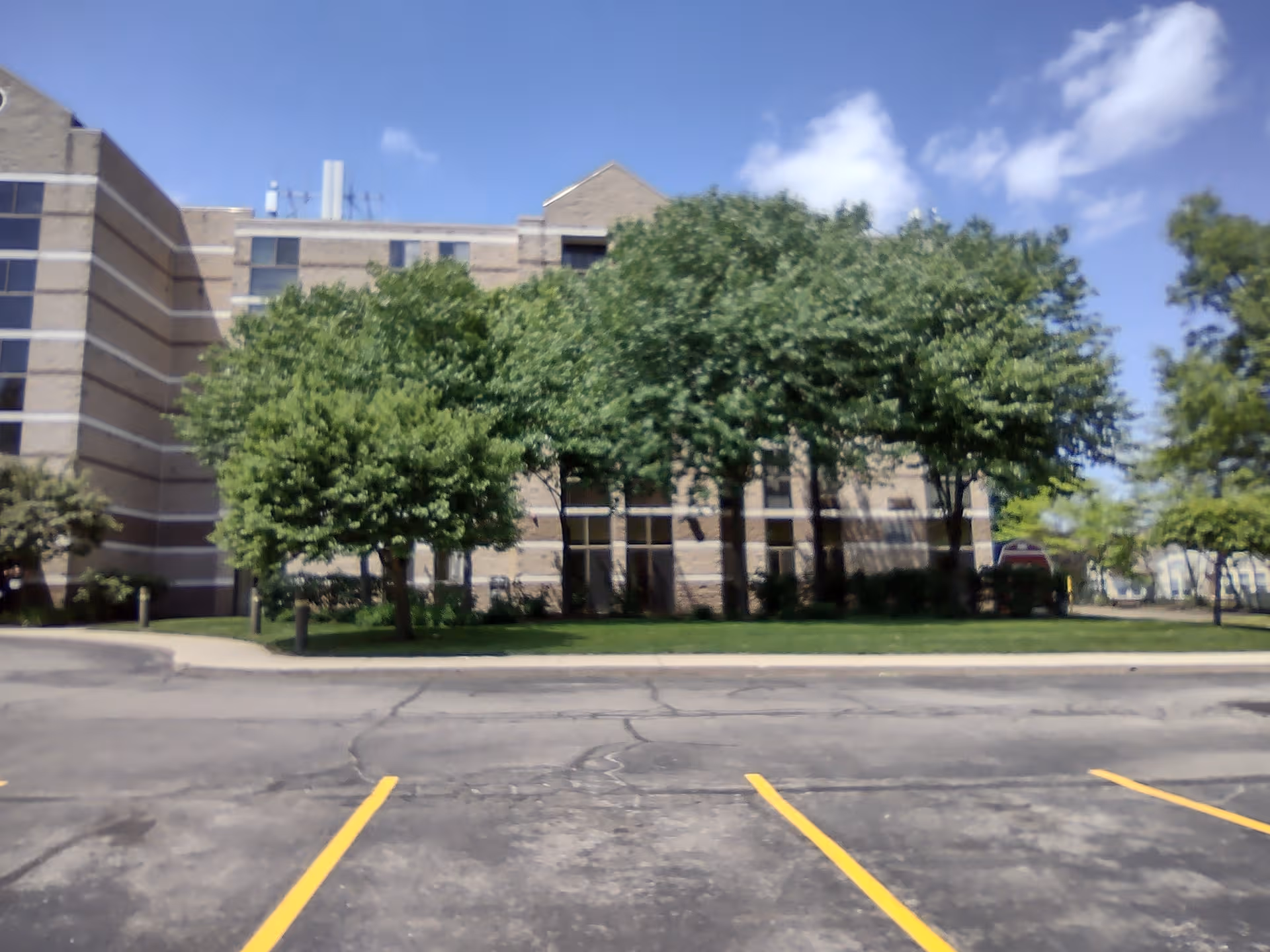 Exterior view of The Westland House with trees, parking lot, and a brick building.