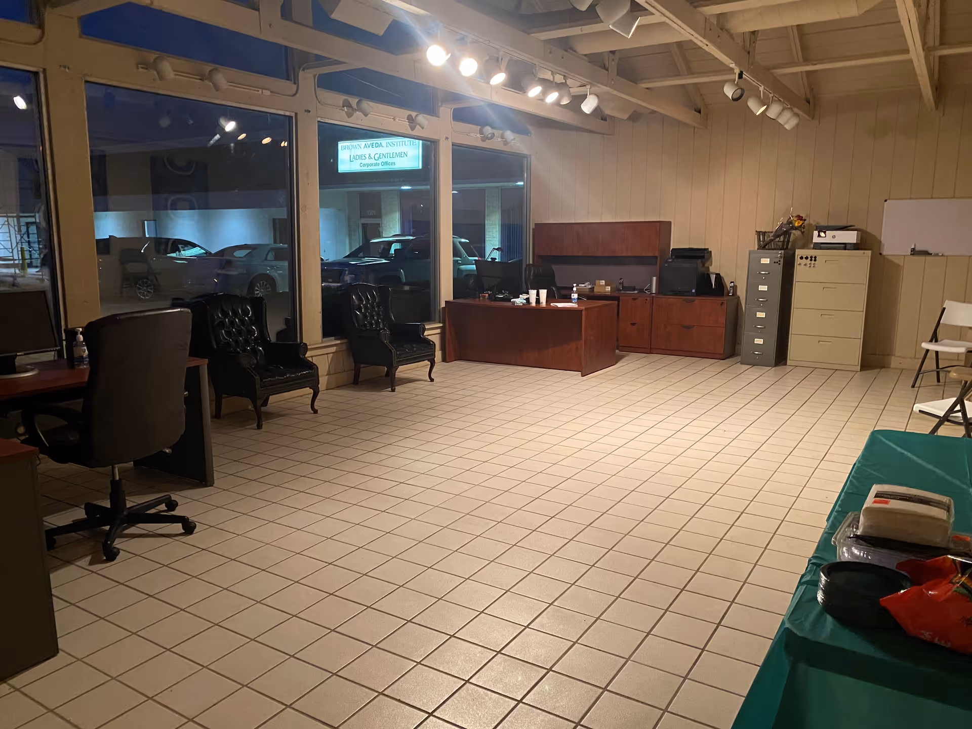 Interior lobby area with desks, chairs, filing cabinets, and large windows.