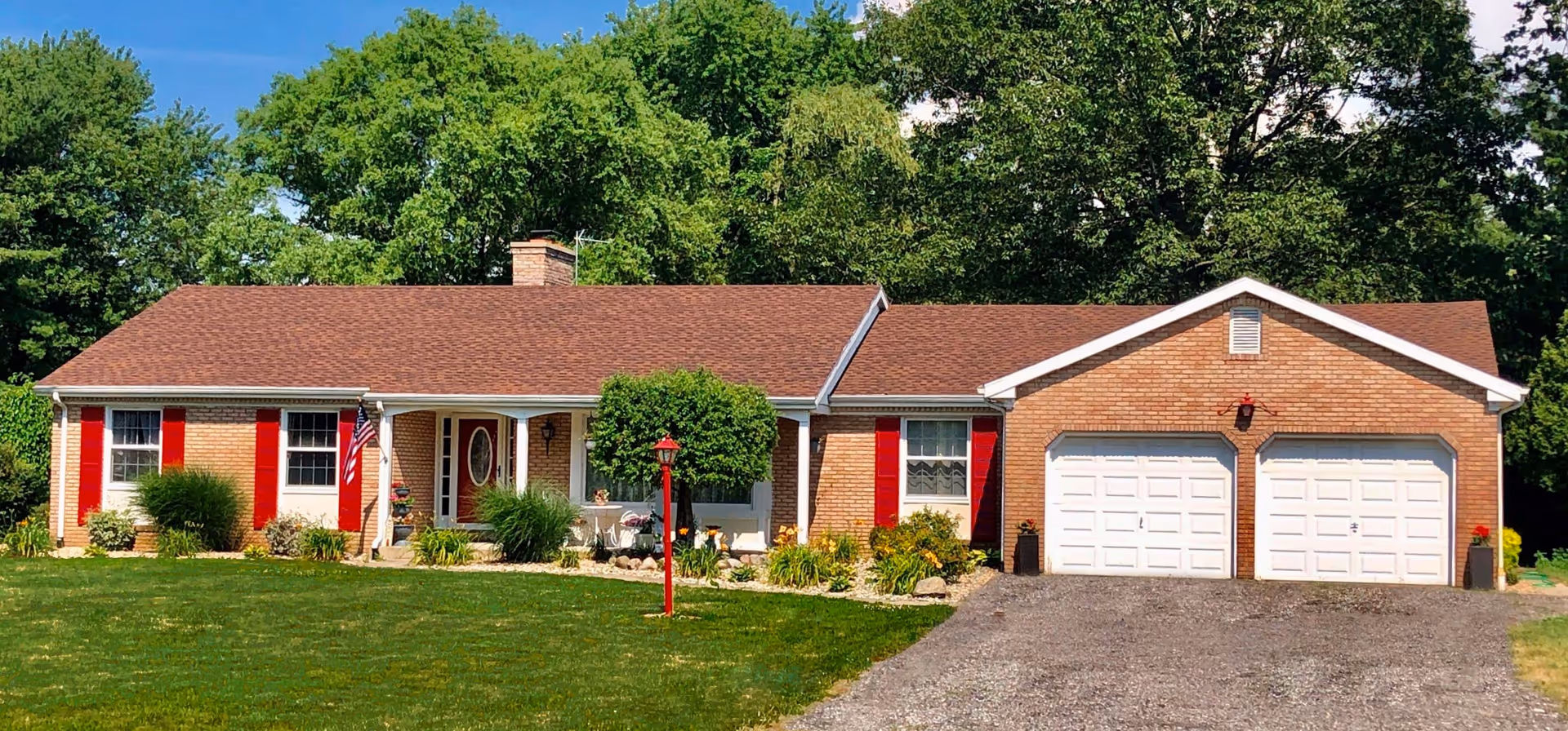 Single-story brick facility with red shutters, a two-car garage, and a green lawn.
