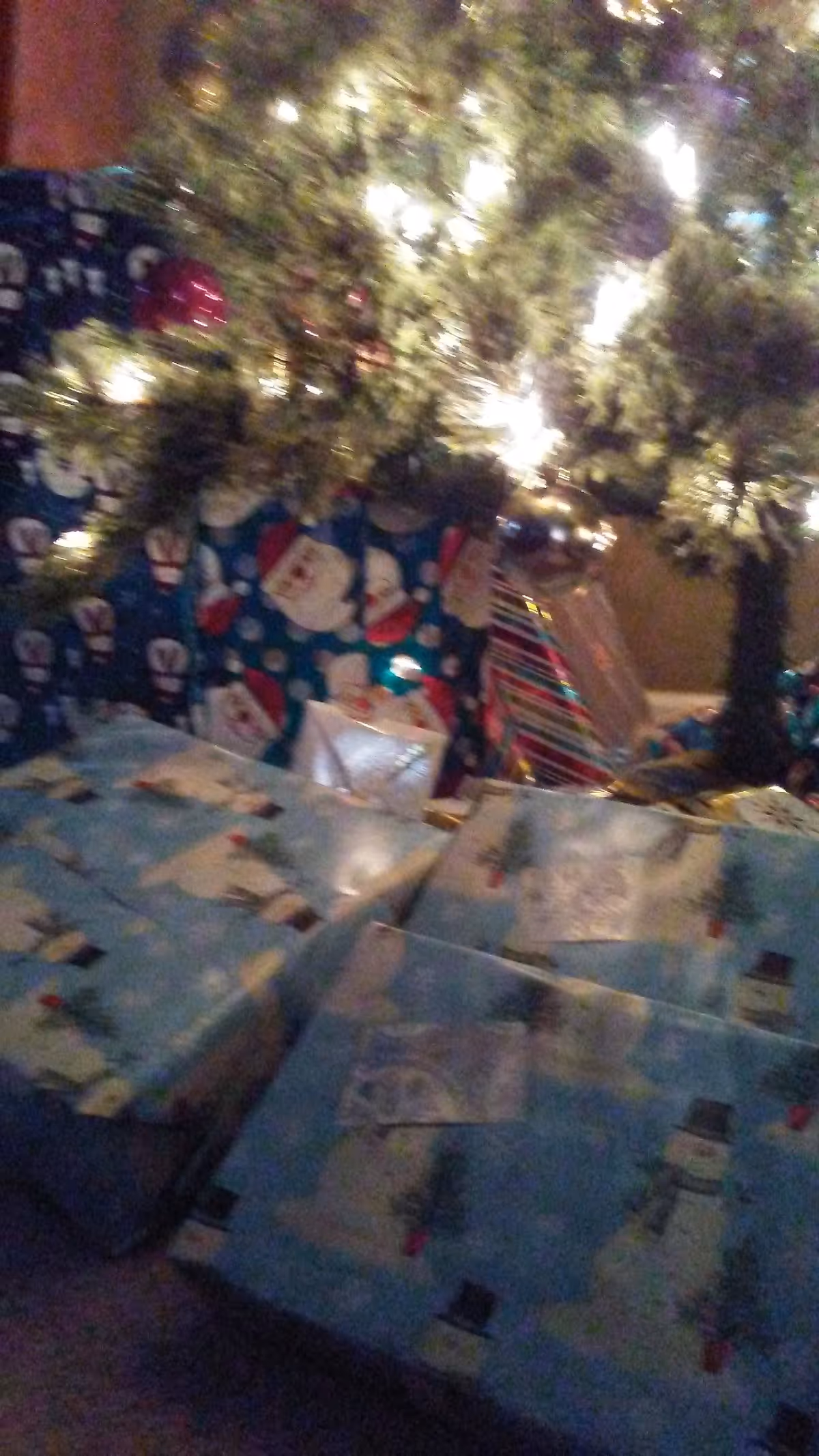 Indoor scene with a decorated Christmas tree and many wrapped presents under it.