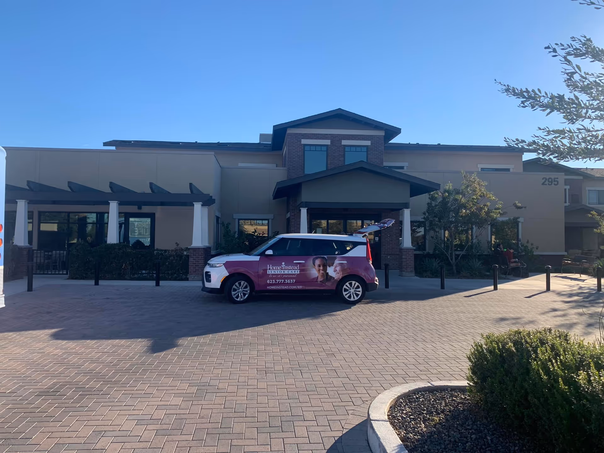 Exterior view of Home Instead facility with a branded van parked at entrance.