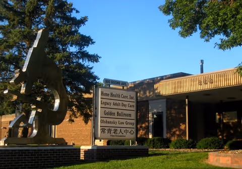 Exterior view of Home Health Care, Inc. building with a sign and abstract sculpture.