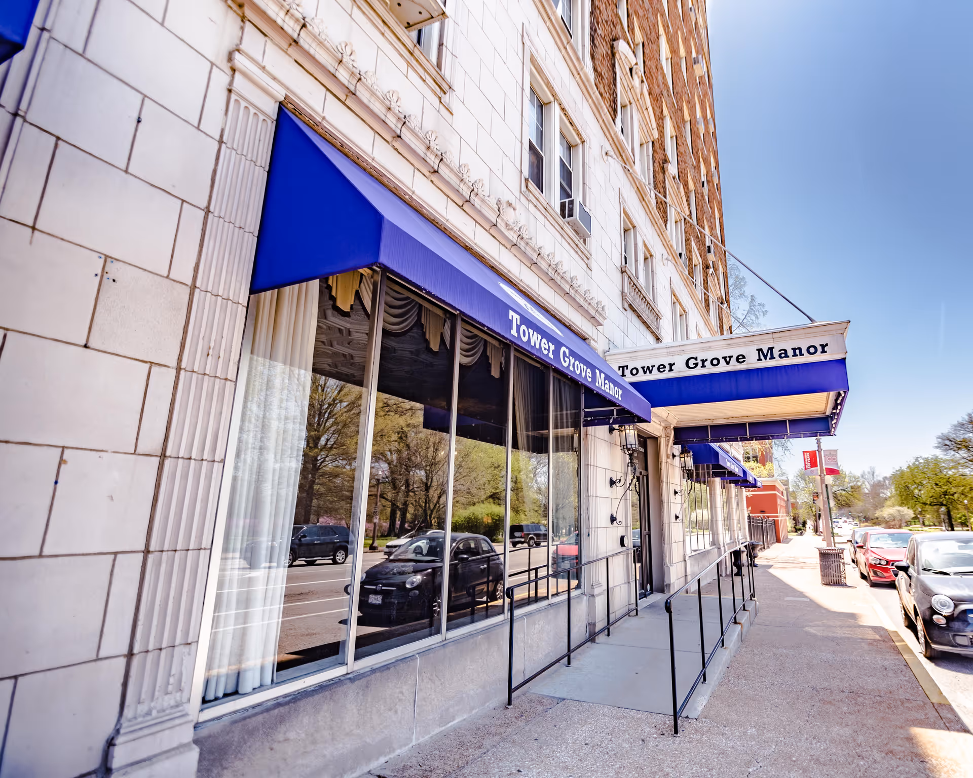 Exterior view of Tower Grove Manor storefront with blue awnings along the sidewalk.