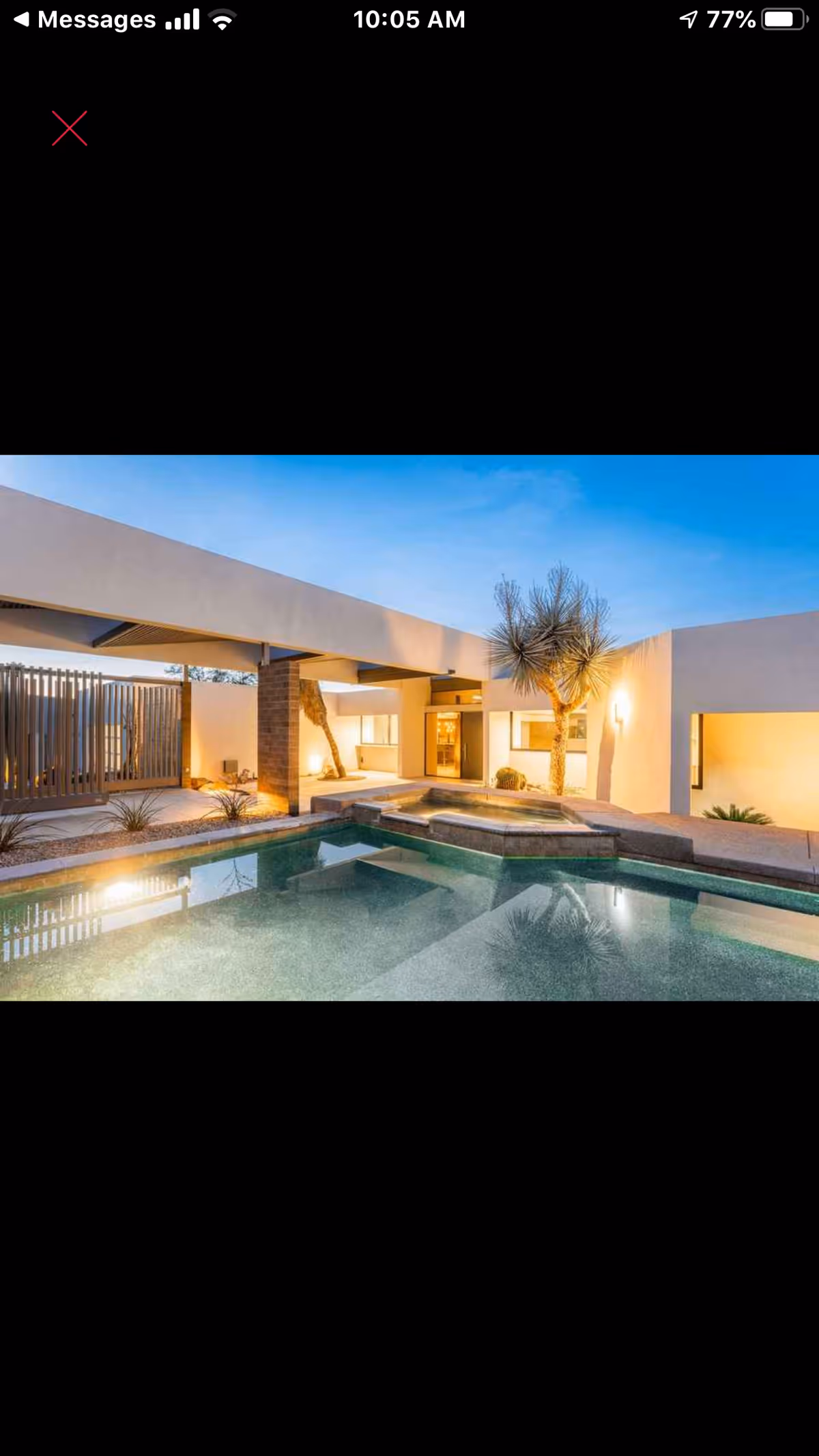 Modern senior living facility exterior with a rectangular pool and desert landscaping.