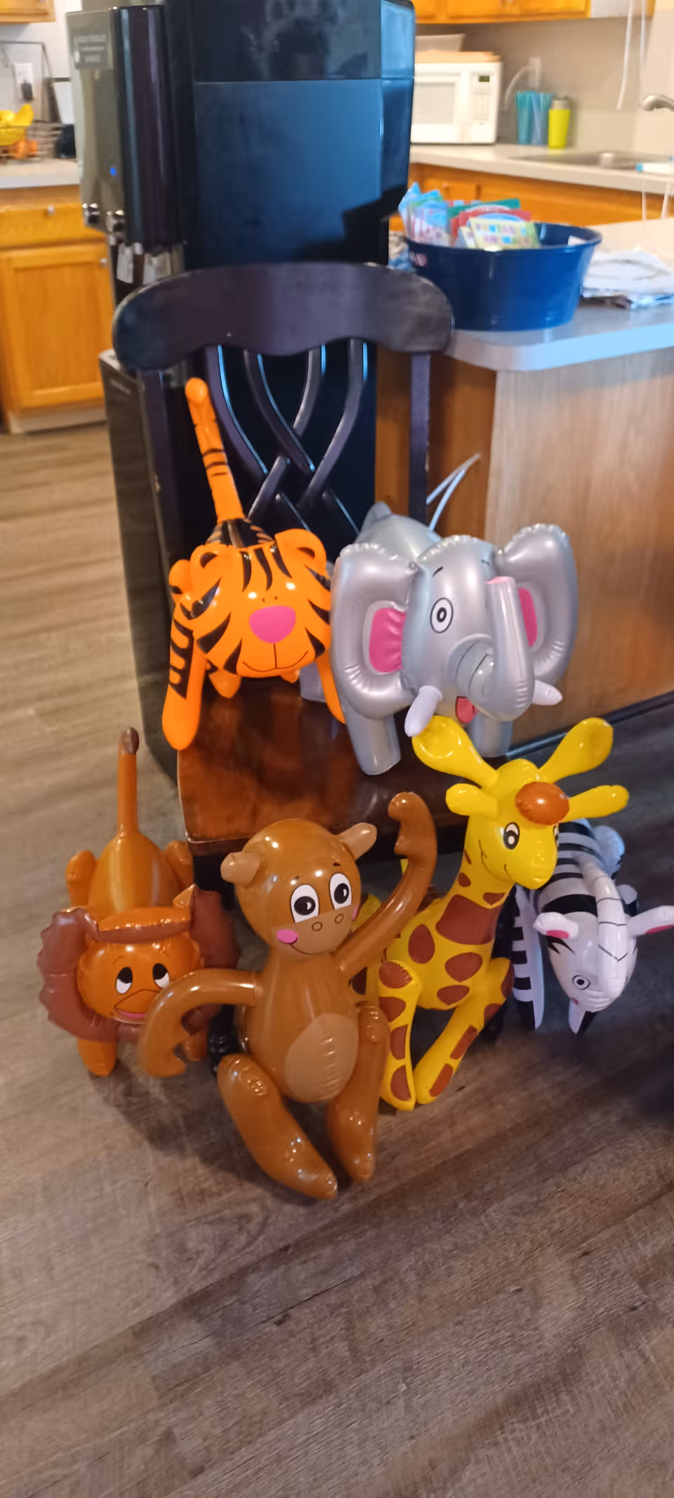 Colorful inflatable animal toys clustered near a chair in a kitchen-like common area.