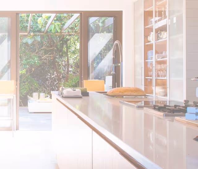 Bright modern kitchen with island, sink, and glass doors to a sunny outdoor patio.