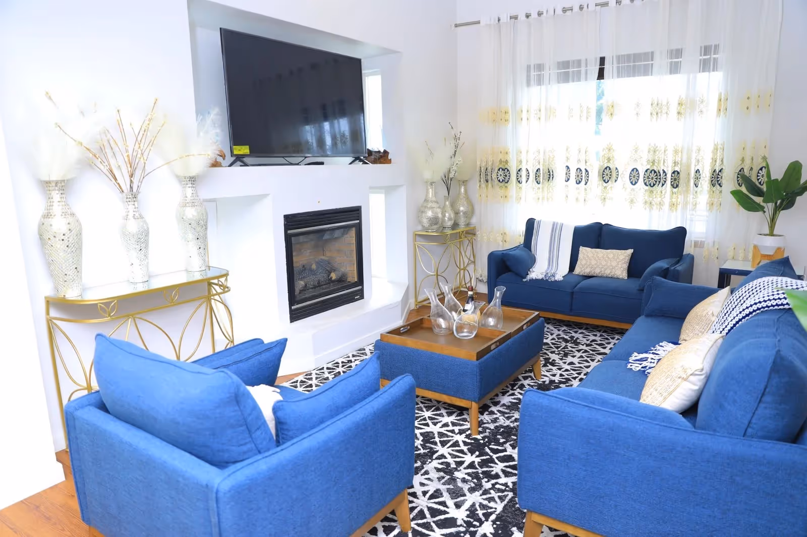 Bright, modern living room with blue couches, a fireplace, and a mounted television.