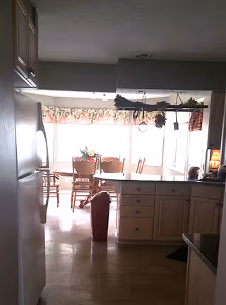 View of a kitchen with cabinets, refrigerator, island, and dining area in background.