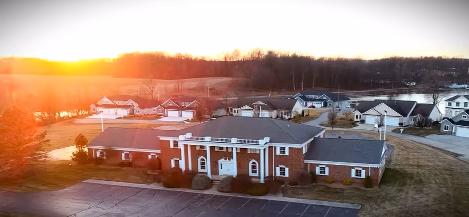 Aerial view of a brick senior living facility with a central entrance and surrounding homes.