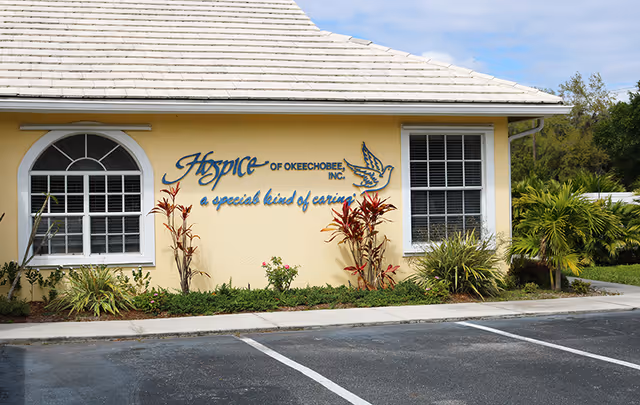 Exterior view of a yellow hospice building with a 'Hospice of Okeechobee' sign.