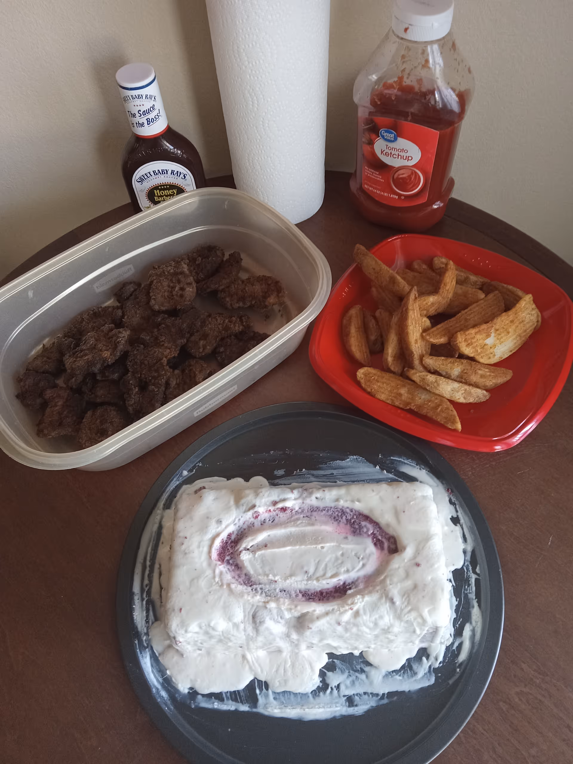Assorted foods on a table: fried meat bites, fries, and a frosted cake.