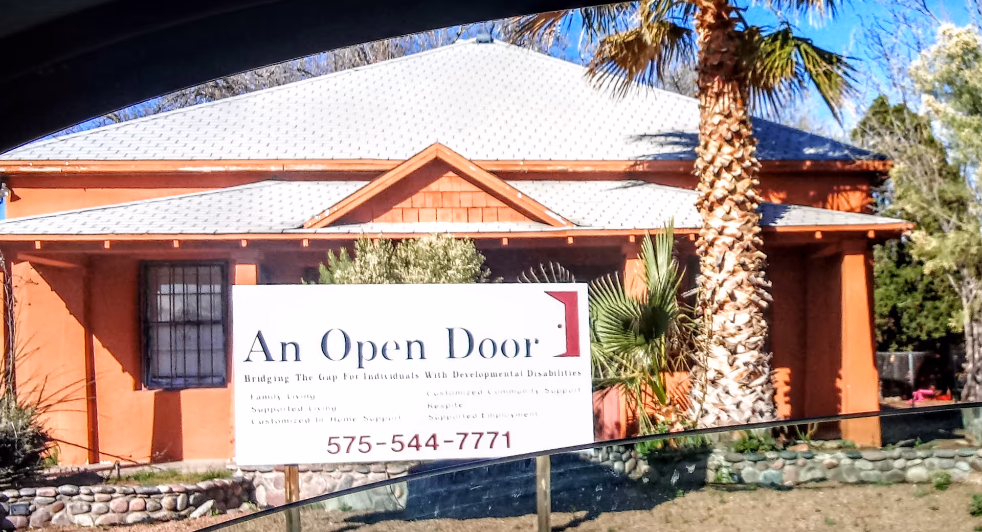 Orange building front with a large white sign reading An Open Door LLC