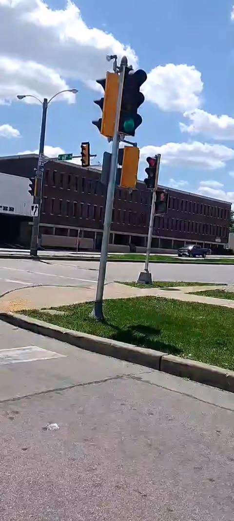 Street scene with traffic lights and a brick building under a blue sky.
