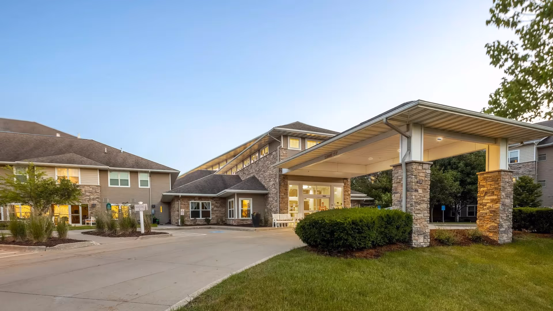 Exterior view of Independence Village of Waukee with a covered entrance and stone pillars.