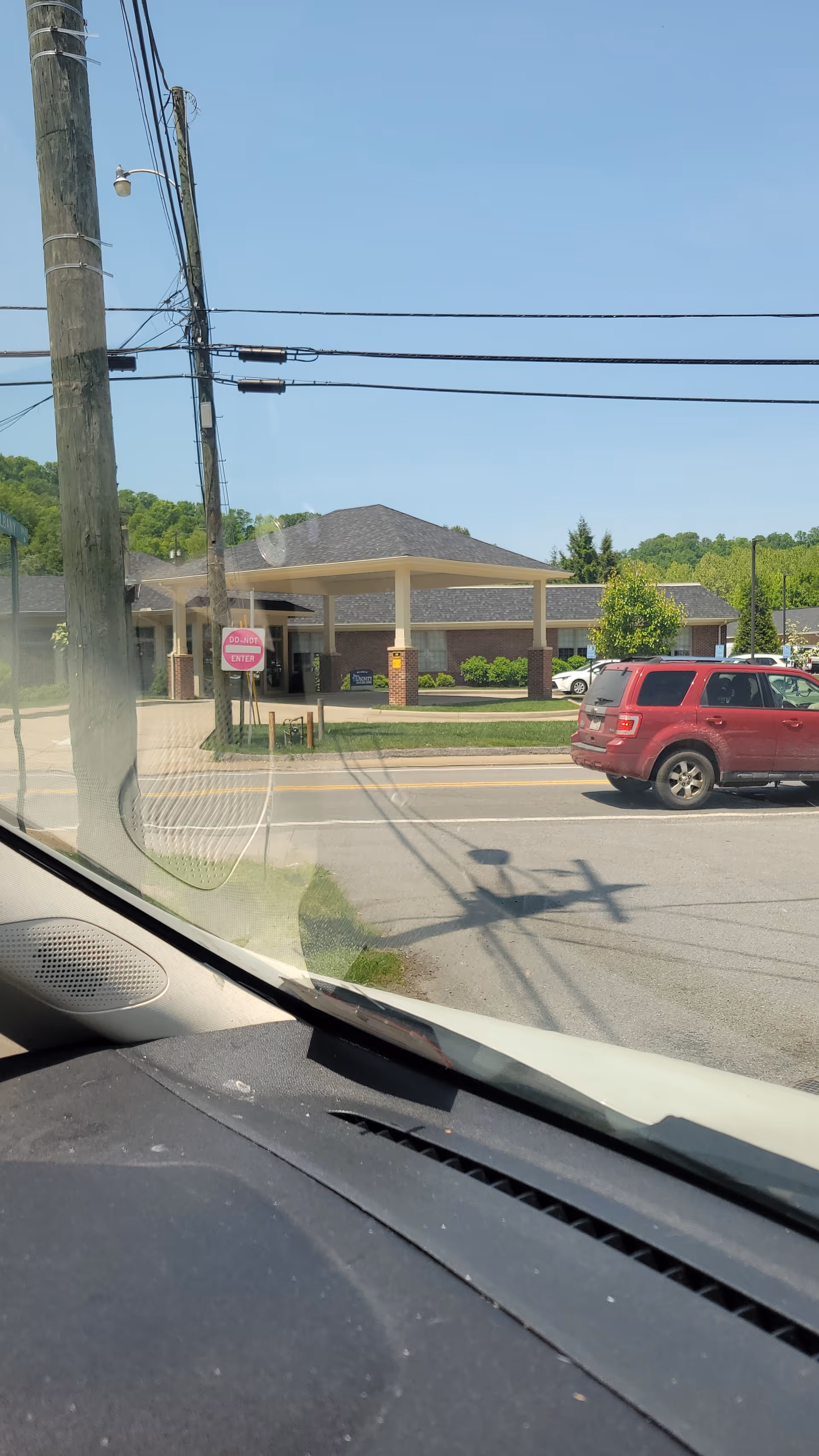 Exterior view of a hospice front entrance with a covered drive and parked vehicles.