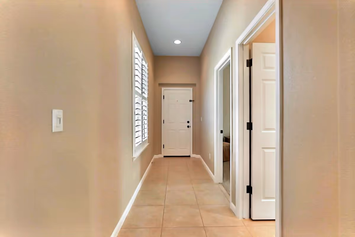 A clean beige hallway inside a senior living facility with doors along the sides.
