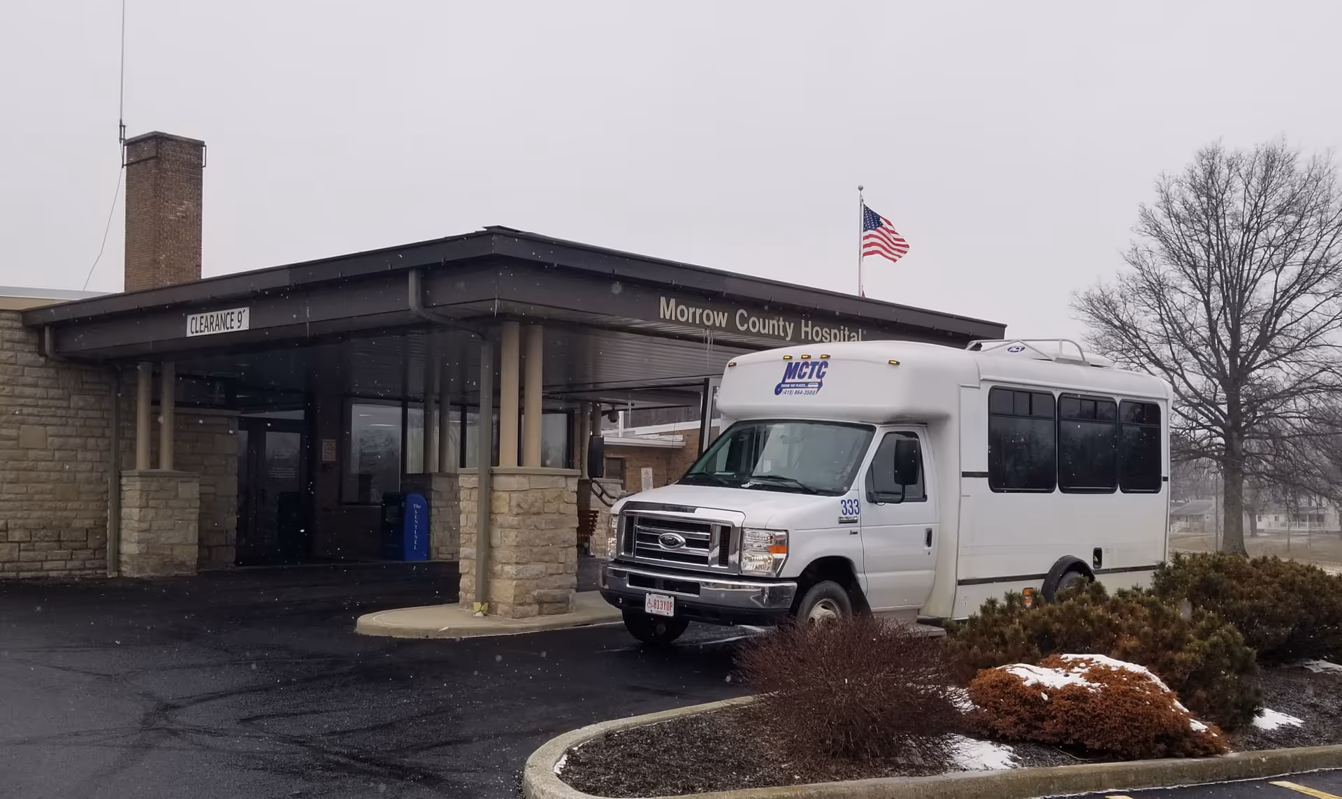 Front view of Morrow County Hospital entrance with a white van parked near the curb.
