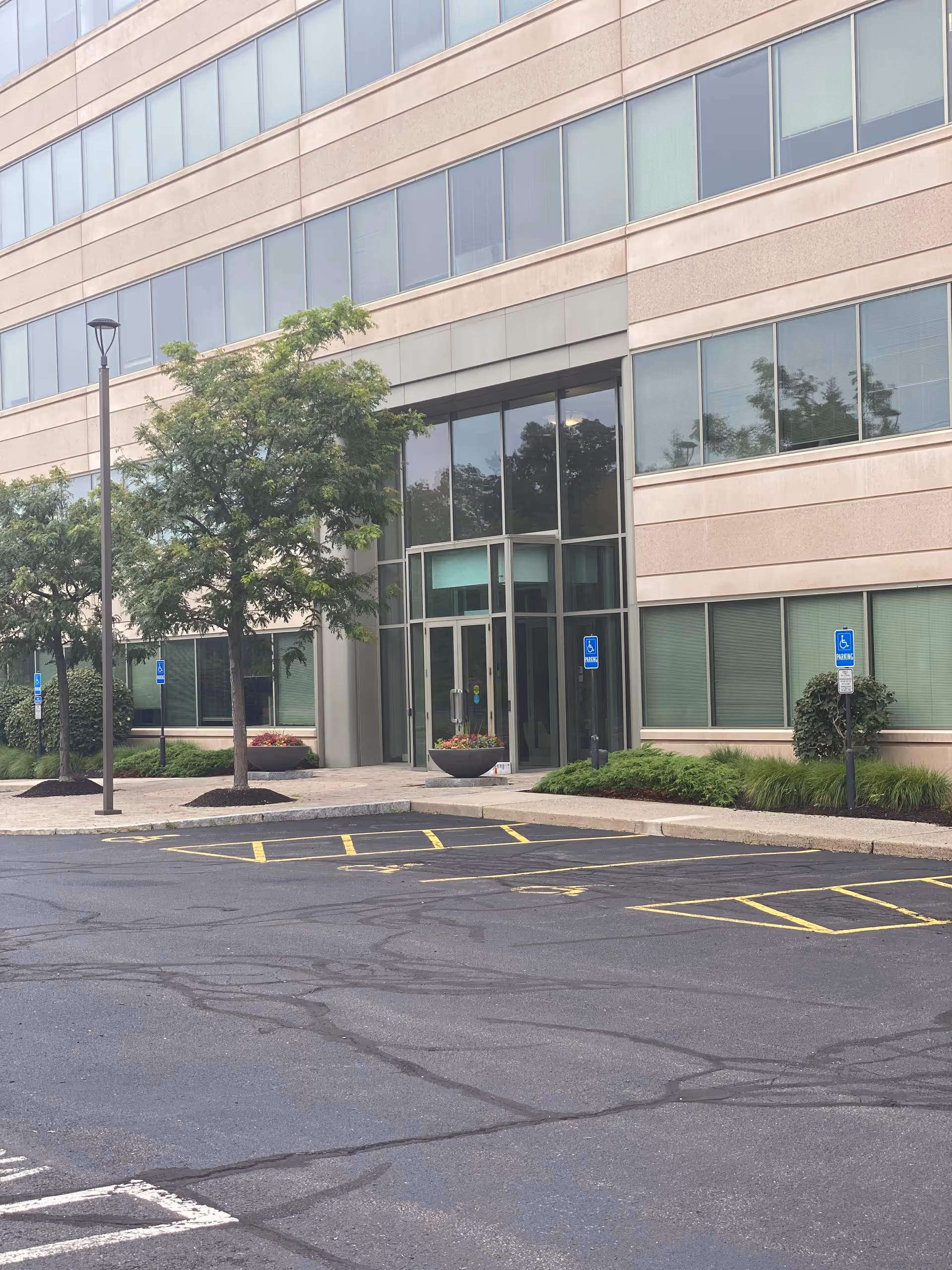 Exterior view of a modern building entrance with glass doors and a parking lot