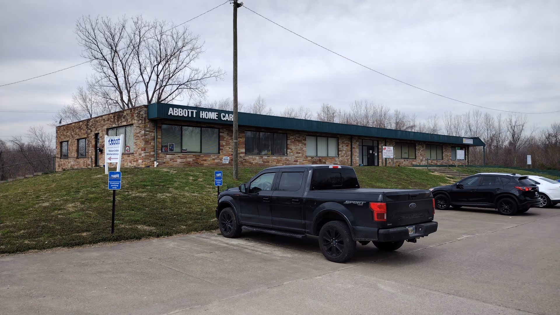 Exterior view of Abbott Home Care building with parking lot and vehicles in front.