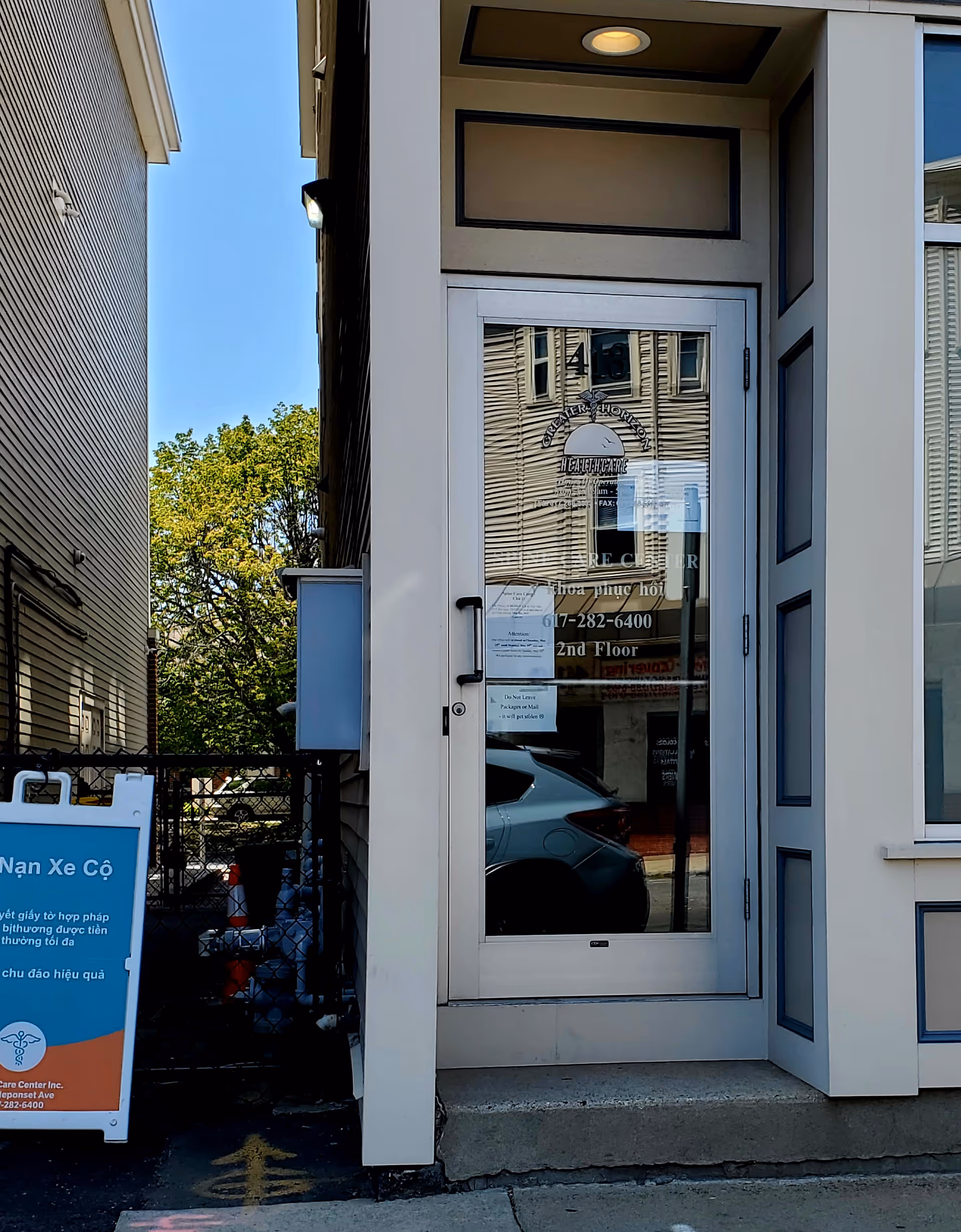 Exterior view of a building entrance with glass door and signage.