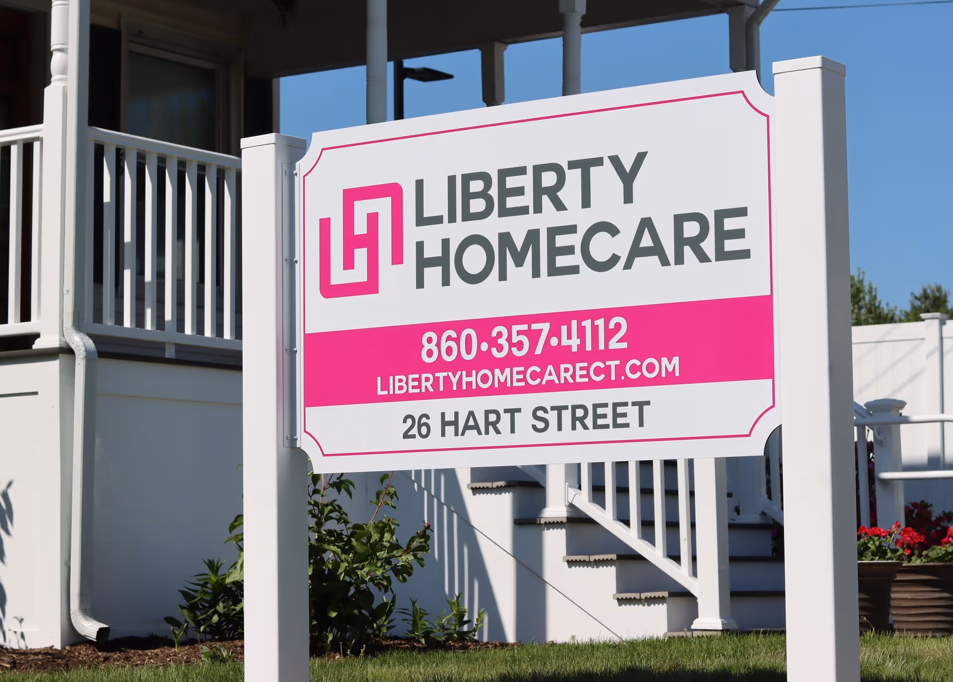 Large LIBERTY HOMECARE sign on front lawn with white porch stairs and railing.