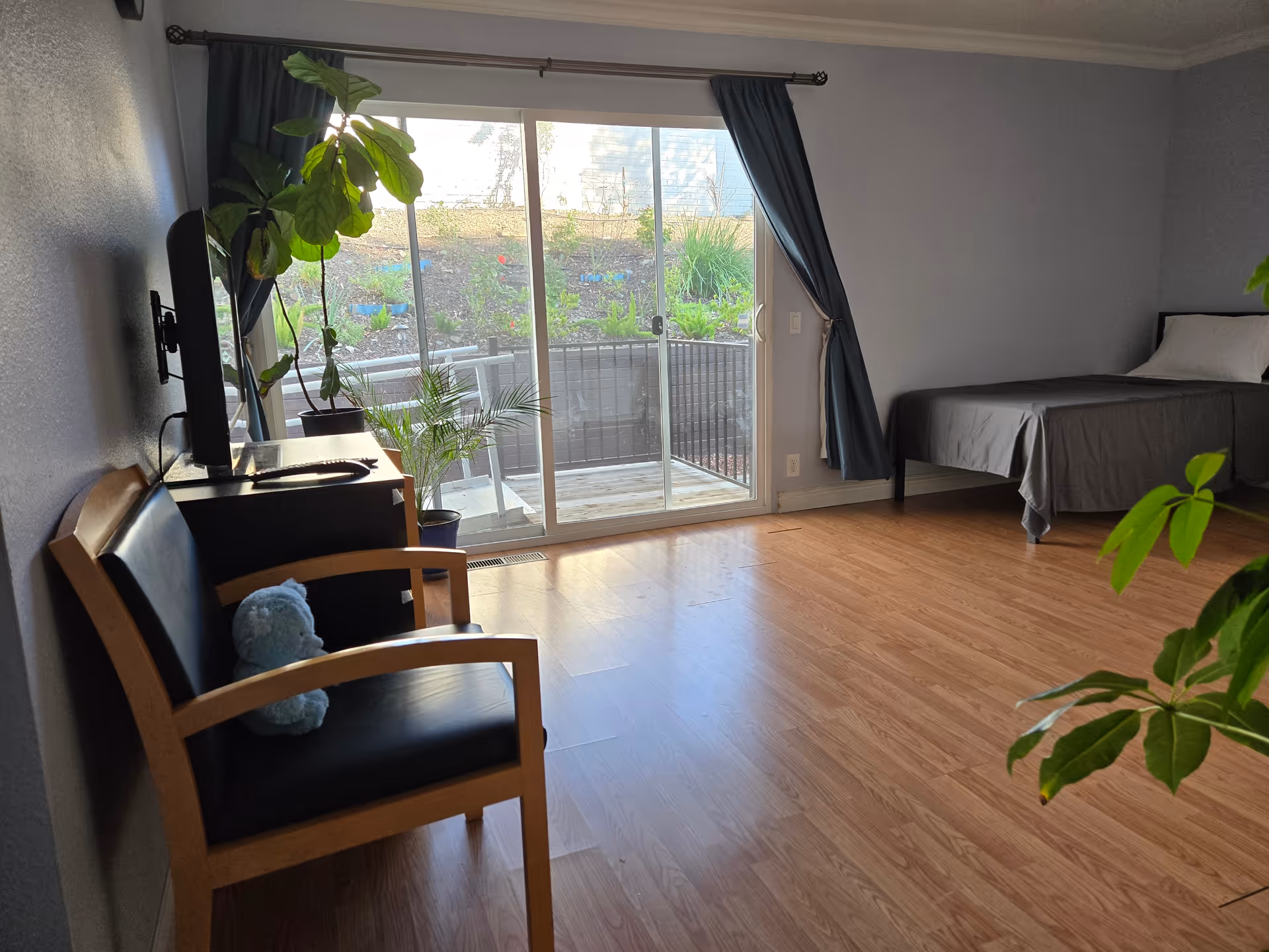 Bedroom in a senior living unit with sliding balcony door and plants.